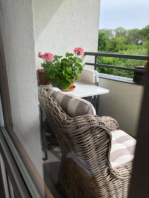 Szary fotel z rattanu na balkonie